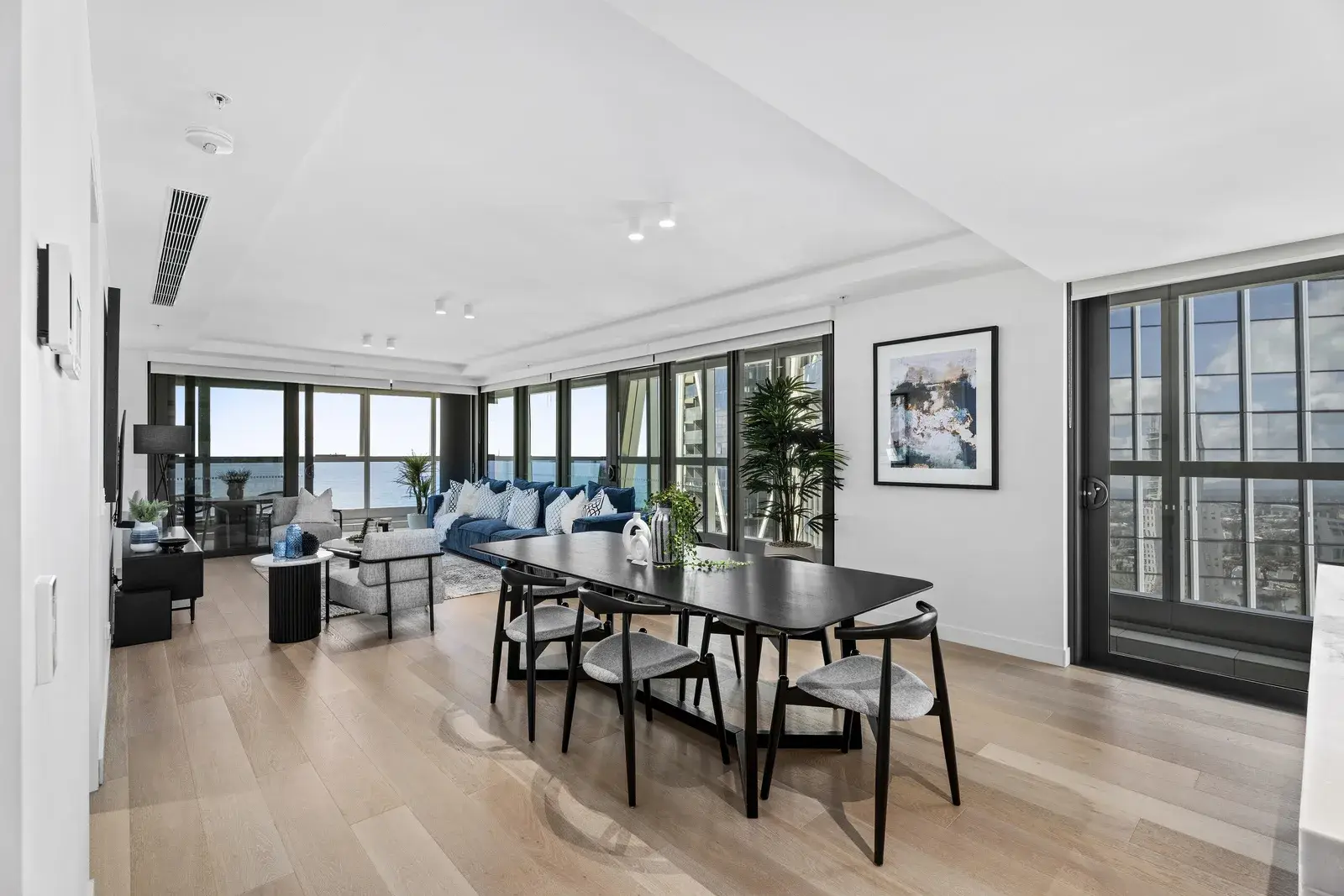 Jewel Residences open-plan living and dining with ocean views, black dining setting and blue sofa