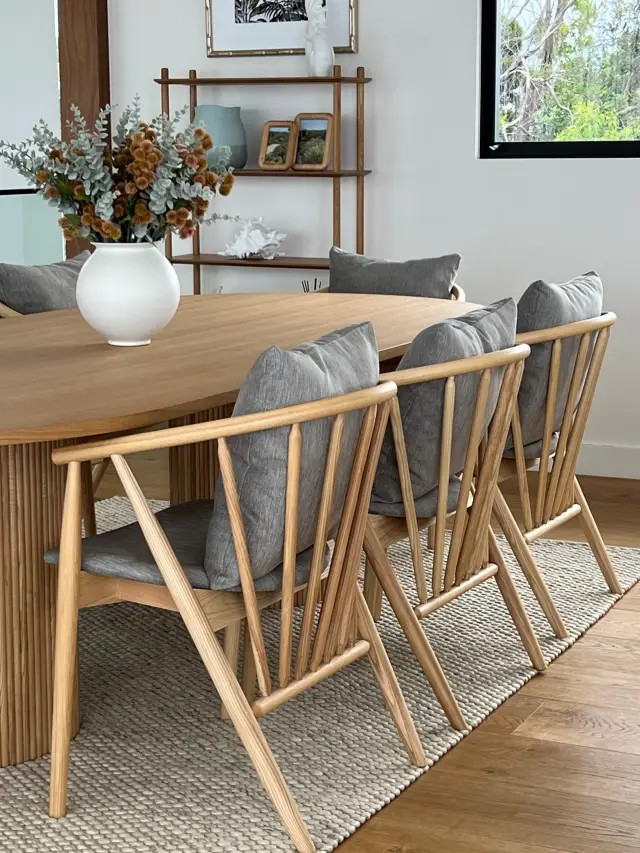 Dining area with oval oak table, grey cushioned spindle chairs and woven jute rug