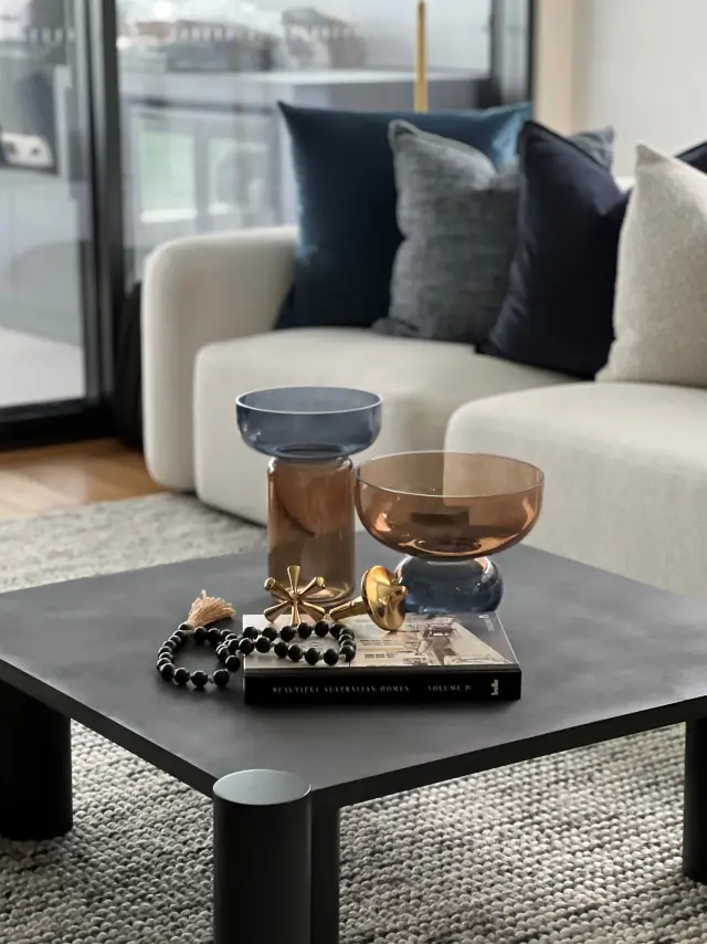 Coffee table styling with amber glass vessels, brass accents and architecture book on charcoal concrete table