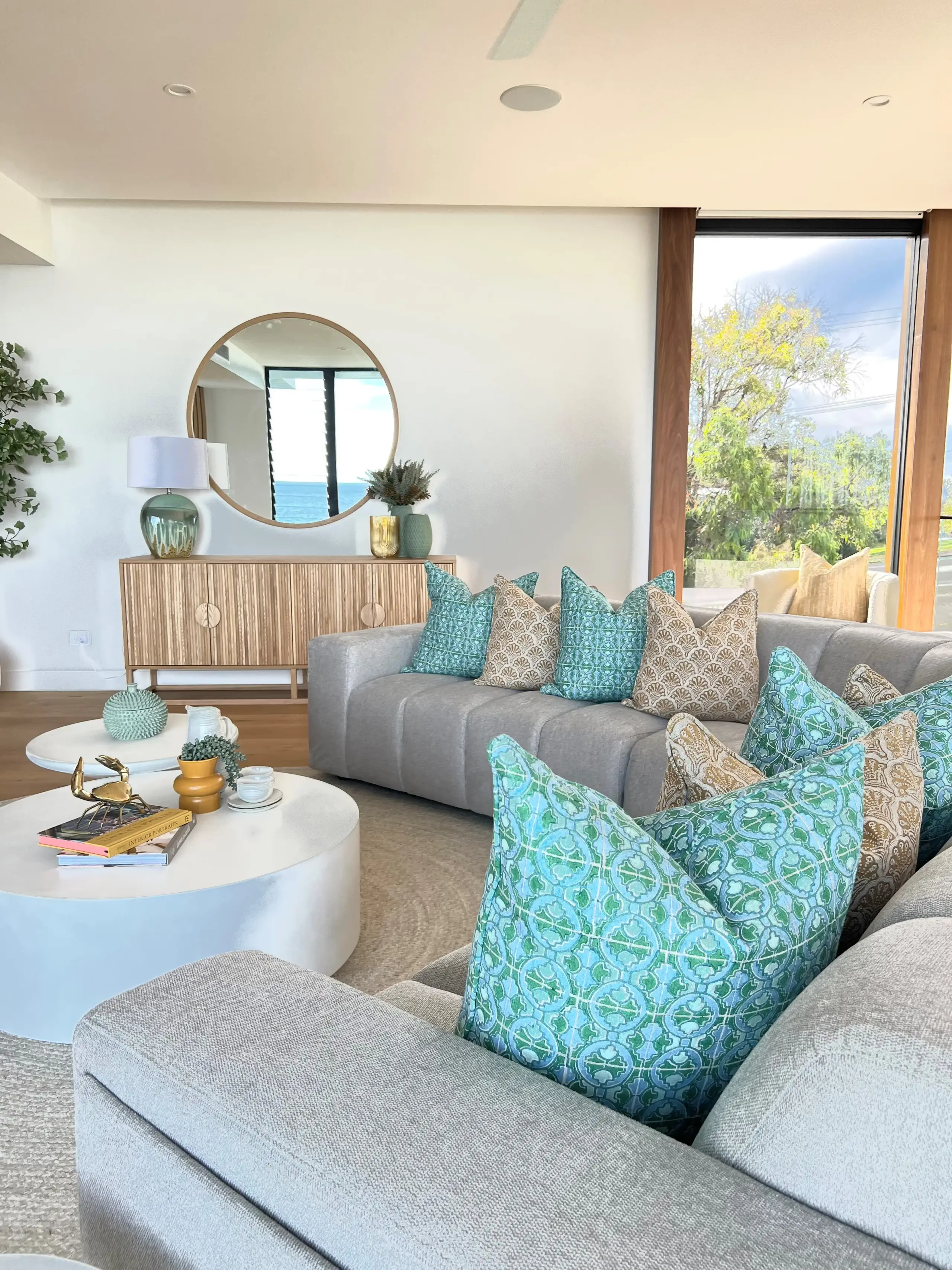 Peregian Beach living room with grey sofa, turquoise patterned cushions and oak sideboard