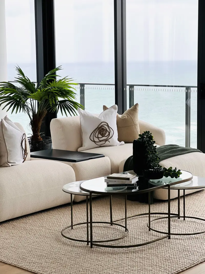 Sandbar display suite living area with cream sofa, marble nesting tables and ocean views
