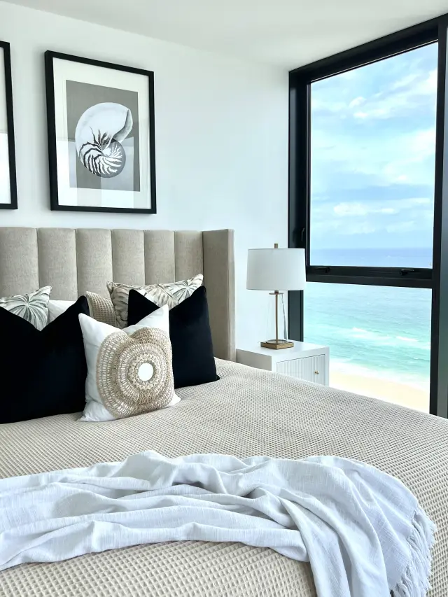 Master bedroom with channel-tufted bedhead, nautilus shell artwork and ocean views