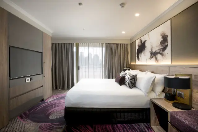 King room with statement abstract artwork, backlit timber headboard and city outlook