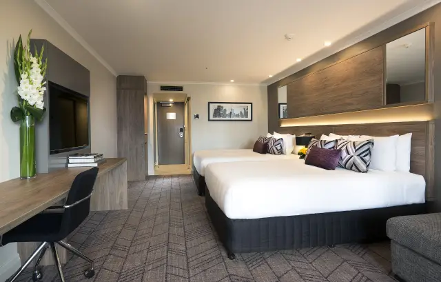 Twin guest room with two queen beds, timber headboard wall and desk with integrated joinery